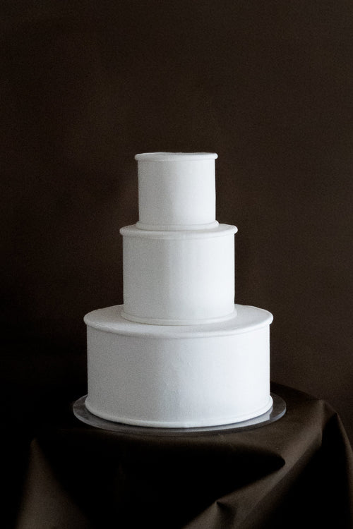 White three-tiered cake on a dark background