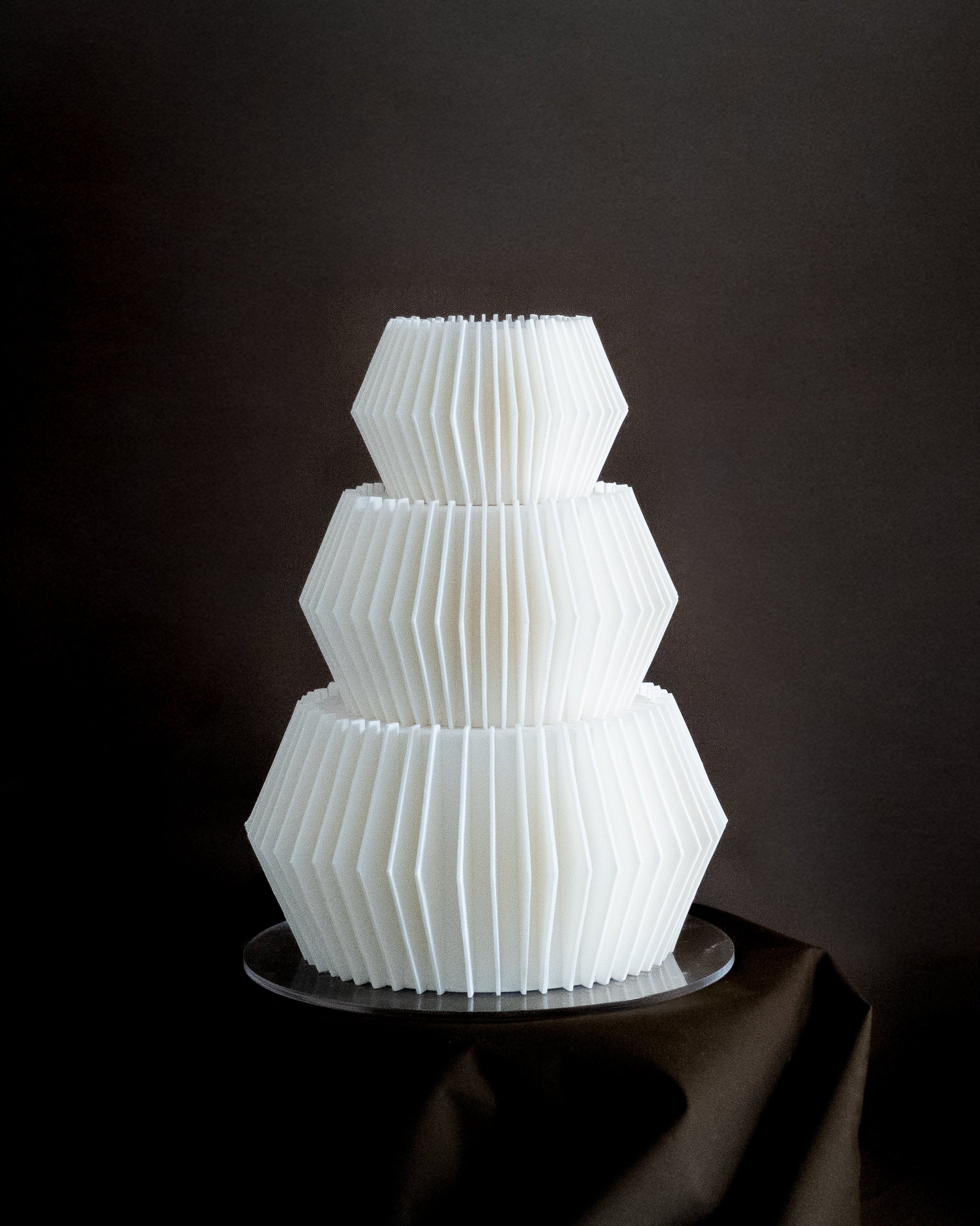 White cake sculpture of a multi-tiered cake on a dark background